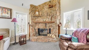 A stone fireplace with a mantel shelf, a couch, and a lamp. - Two-story dog-friendly getaway with WiFi, wood-burning fireplace, & washer/dryer (Fraser)