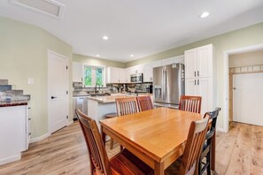 A kitchen with white cabinets, a wooden dining table, and a stainless steel refrigerator. - Two-story dog-friendly getaway with WiFi, wood-burning fireplace, & washer/dryer (Fraser)