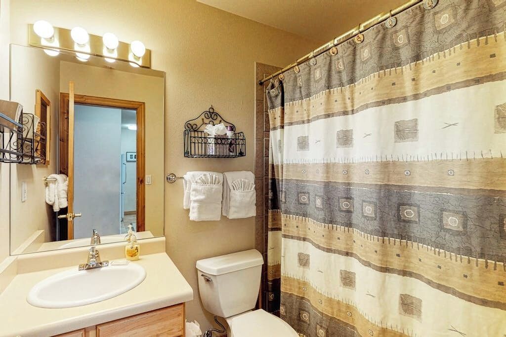 Une salle de bain équipée d’un lavabo, d’un miroir, d’un porte-serviettes et d’un rideau de douche.