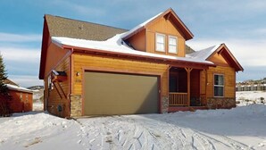A two-story wooden house with a garage, surrounded by snow. - Getaway with fireplace, gas fire pit, shared pool/hot tub-minutes to ski & golf (Granby)