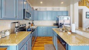 A kitchen with blue cabinets, granite countertops, stainless steel appliances, and a wooden floor. - Getaway with fireplace, gas fire pit, shared pool/hot tub-minutes to ski & golf (Granby)