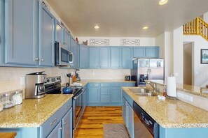 Eine Küche mit blauen Schränken, Granit-Arbeitsplatten, Edelstahlgeräten und Holzboden.