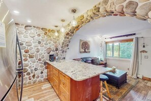 Eine Küche mit Steinwand, Holzschränken und einer zentralen Kochinsel.