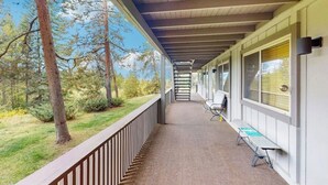 Eine überdachte Veranda mit Blick auf Bäume und Gras, eine Bank und ein Tisch.