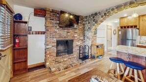 Eine Küche mit steinbogigem Durchgang, Kamin, Holzausstattung und einem Edelstahlkühlschrank.