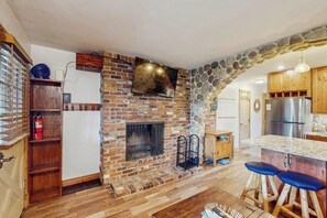 Eine Küche mit steinbogigem Durchgang, Kamin, Holzausstattung und einem Edelstahlkühlschrank.