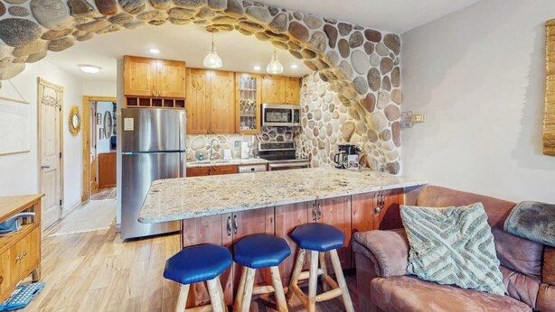 Eine Küche mit Steingewölbe, Holzschränken, einem Edelstahlkühlschrank und einer Bar mit Hockern.