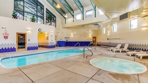 An indoor swimming pool with a blue and white tiled wall, a sunroof, and lounge chairs. - Conveniently Located Condo with Pool, Hot Tub & Sauna - Near Slopes & Lake (Silverthorne)