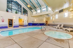 An indoor swimming pool with a blue and white tiled wall, a sunroof, and lounge chairs. - Conveniently Located Condo with Pool, Hot Tub & Sauna - Near Slopes & Lake (Silverthorne)