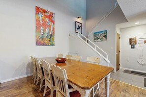 Ein Essbereich mit Holztisch und -stühlen, einer Treppe und Bildern an der Wand.