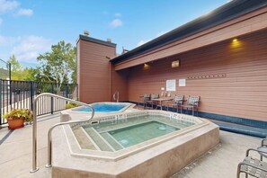 Ein Whirlpool und eine Außen-Sitzgelegenheit mit Pool, umgeben von einer Holzwand und einem Metallzaun.