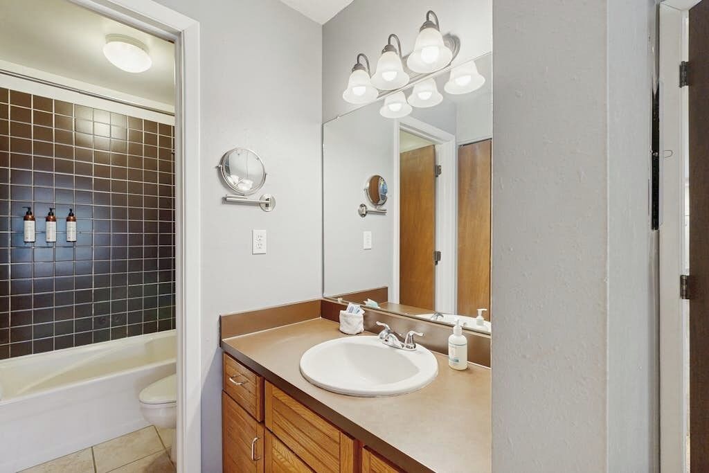 Un baño con bañera, lavamanos, espejo y zona de ducha.
