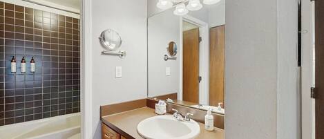 Un baño con bañera, lavamanos, espejo y zona de ducha.