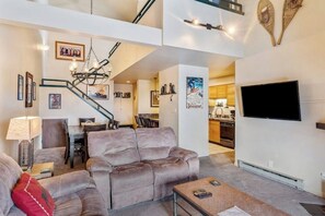 Ein Wohnzimmer mit einer Couch, einem Couchtisch und einem an der Wand befestigten Fernseher.