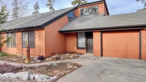 A modern two-story house with a sloped roof, a garage, and a front yard with rocks and a small tree. - Spacious lodge-style duplex with private hot tub - near hiking, skiing, & more (Silverthorne)