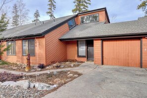 Ein modernes, zweistöckiges Haus mit Satteldach, Garage und einem Vorgarten mit Steinen und einem kleinen Baum.