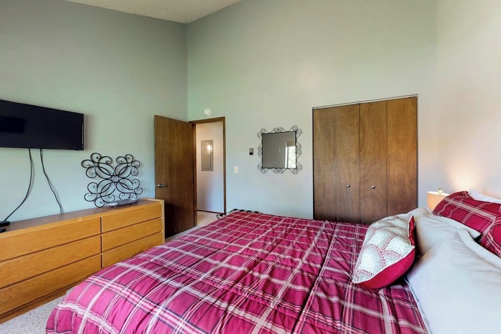 A bedroom with a bed, dresser, TV, wardrobe, and a mirror.