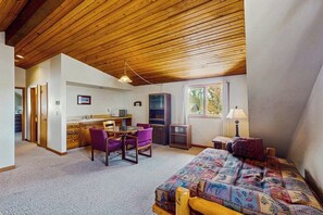 Ein Schlafzimmer mit einem Bett, einem Schreibtisch, Stühlen und einer Küchenzeile.