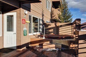 Un edificio con una terrazza in legno, una vasca idromassaggio e una porta con un cartello.