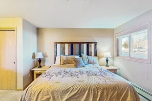 Una camera da letto con un letto, due comodini con lampade, una testiera in legno e una finestra vista.