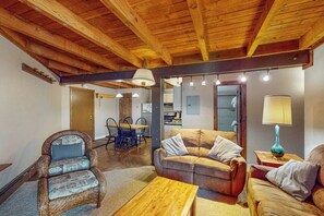 Ein gemütliches Wohnzimmer mit Holzboden, einer Couch, einem Sessel, einem Couchtisch und einer Lampe.