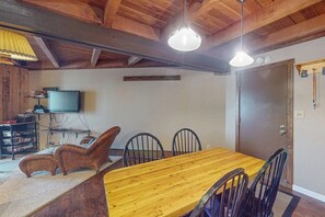 A dining area with a wooden table and chairs, a television on a stand, and a door with a handle. - Wildernest condo with sauna and tennis, 5 miles to Lake Dillon (Silverthorne)