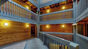 Monitasoinen puinen sisustus, jossa on keskeisellä paikalla sijaitseva portaikko, kaiteet ja pyöreät valaisimet.