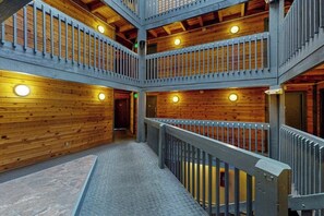 Ein mehrgeschossiges Holzinnere mit einer zentralen Treppe, Geländern und runden Leuchten.