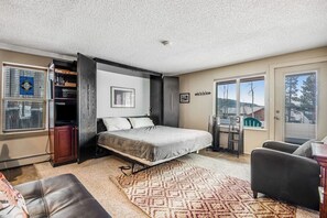 Ein Schlafzimmer mit Bett, Kleiderschrank, Schreibtisch und Fenster.