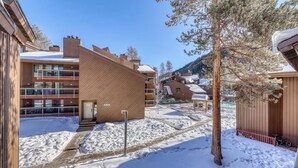 A snow-covered outdoor area with buildings, a tree, and a bicycle. - Cozy condo w/ private balcony, shared pool, & hot tub - close to golf & slopes (Keystone)