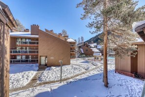 A snow-covered outdoor area with buildings, a tree, and a bicycle. - Cozy condo w/ private balcony, shared pool, & hot tub - close to golf & slopes (Keystone)