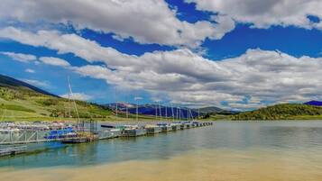 Un puerto deportivo con barcos amarrados, cielo despejado y montañas al fondo.