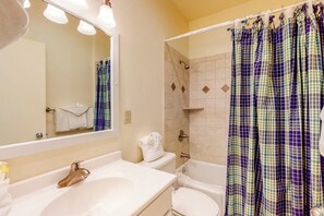 A bathroom with a sink, mirror, toilet, shower, and a checkered shower curtain. - Bright home with fireplace & perfect location steps to hiking trails (Dillon)
