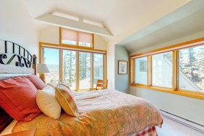 Ein Schlafzimmer mit einem großen Bett, einem Fenster mit Blick auf Bäume und einem Dachfenster.
