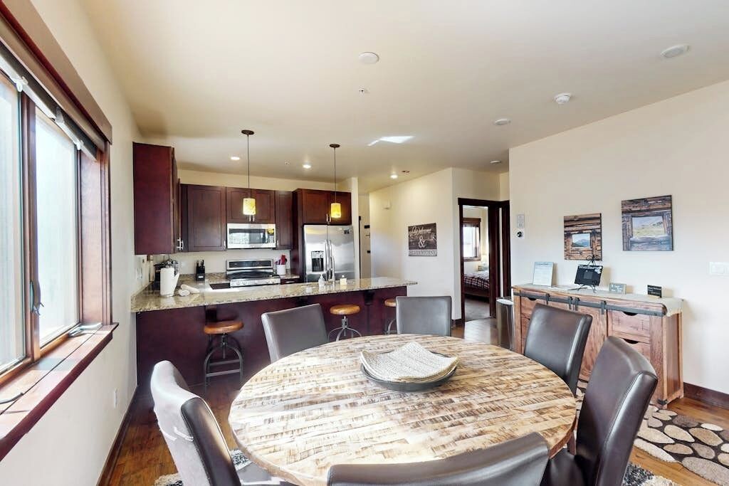 A modern kitchen with dark cabinets, a central island, and pendant lighting.