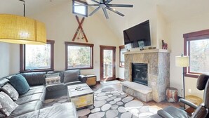 Una sala de estar con chimenea de piedra, sofá de cuero y ventilador de techo.