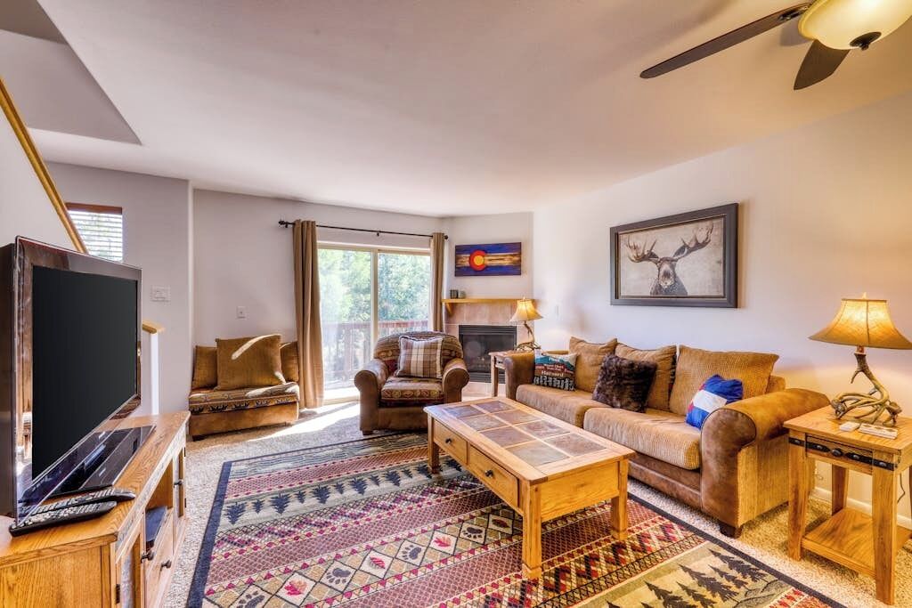 Ein Wohnzimmer mit Fernseher, zwei Sofas, einem Couchtisch und einem Kamin.