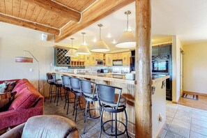A kitchen with wooden beams, a bar area with stools, and a dining table. - Gorgeous Townhouse w/Free WiFi, Private Washer/Dryer, Lake Views - Near Keystone (Dillon)