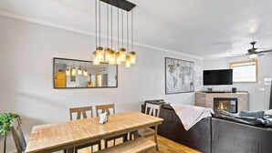 Ett modernt vardagsrum med matplats, soffa, öppen spis och tv.