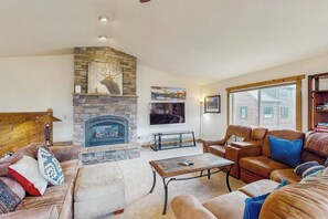Ein gemütliches Wohnzimmer mit Kamin aus Stein, Ledersofas und einem Fernseher.