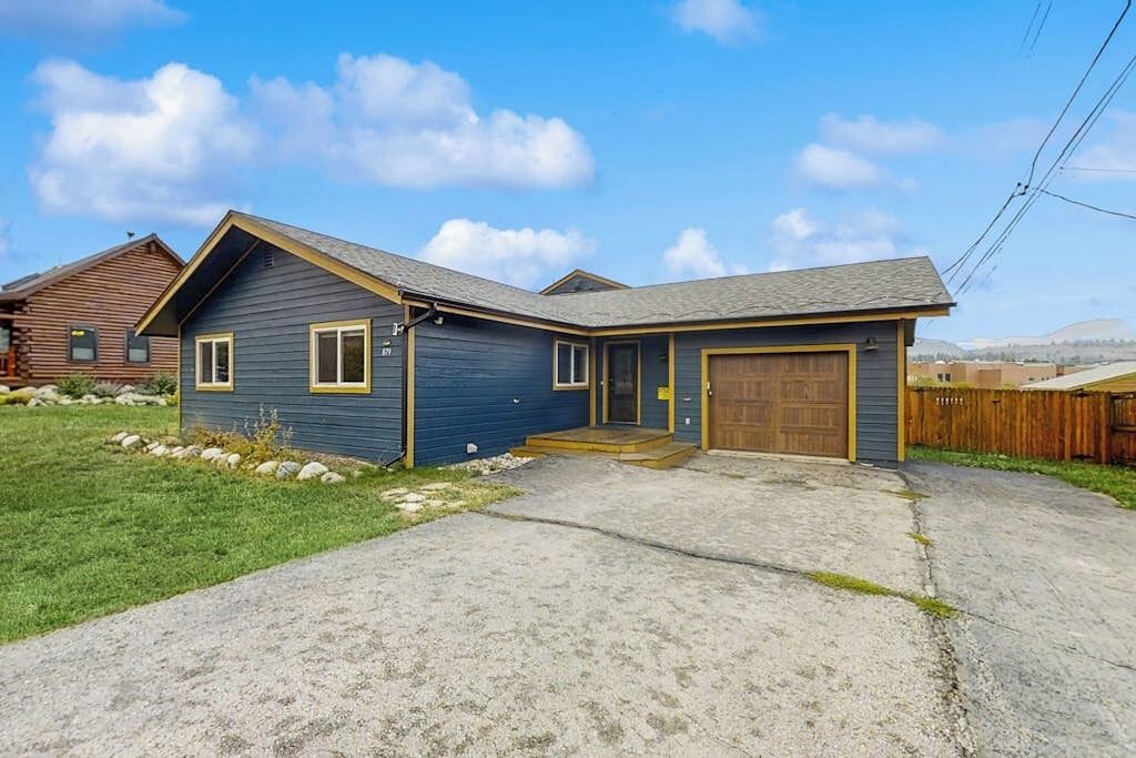 A single-story house with a front garage, a sloped roof, and a front yard with a gravel driveway.