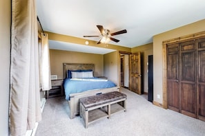 Ein Schlafzimmer mit einem Bett, einer Sitzbank, einem Deckenventilator und Holztüren.