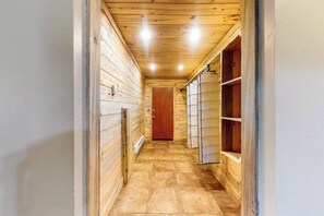 A narrow hallway with wooden walls and a tiled floor, leading to a door at the end. - Mountain view home with deck, wood-burning fireplace, & WiFi - great location (Dillon)