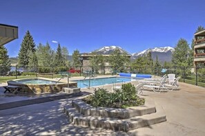 A pool area with a hot tub, lounge chairs, and a view of snow-capped mountains. - Lake & ski view condo | Pool, hot tub, sauna & cozy fireplace (Dillon)