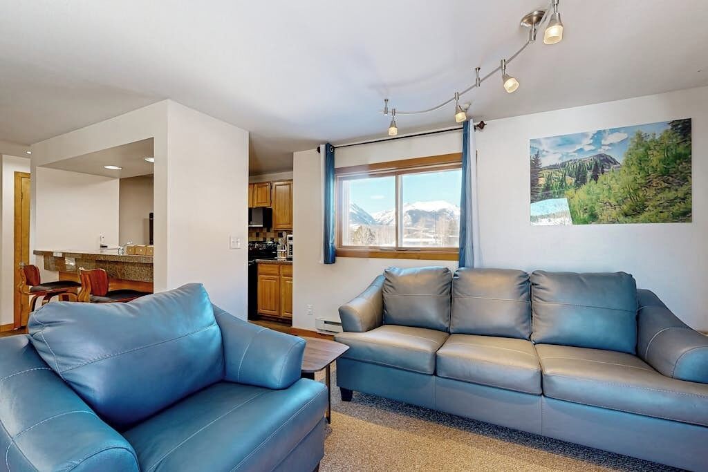 A modern living room with a sofa, a dining area, and a kitchen.