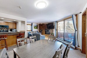 Eine moderne Küche mit Essbereich, Kamin und einer großen Schiebeglastür zu einer Terrasse.