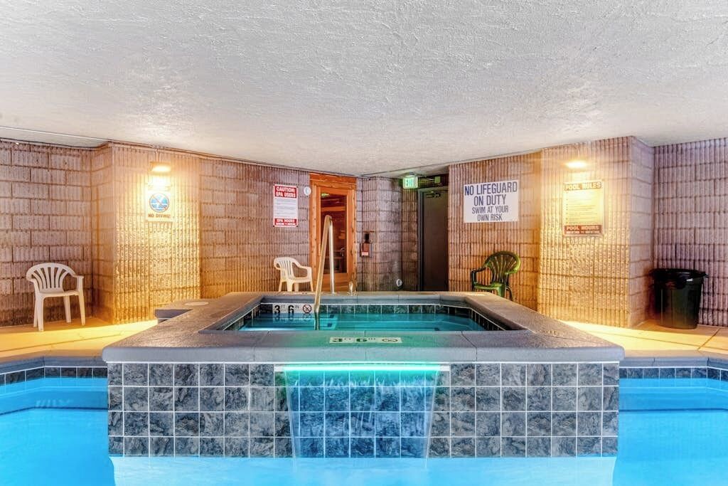 En swimmingpool med kaklade väggar, en skylt med information om badvakten och en stol.