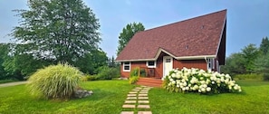 A house with a sloped roof, a front porch, and a pathway leading to the entrance.