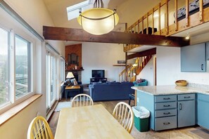 A modern kitchen with a dining area, wooden beams, and a view through large windows. - Top-floor w/ Mountain View (Silverthorne)