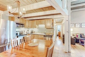 Eine moderne Küche mit Holzschränken, Edelstahlgeräten und einem Essbereich mit Holztisch und Stühlen.